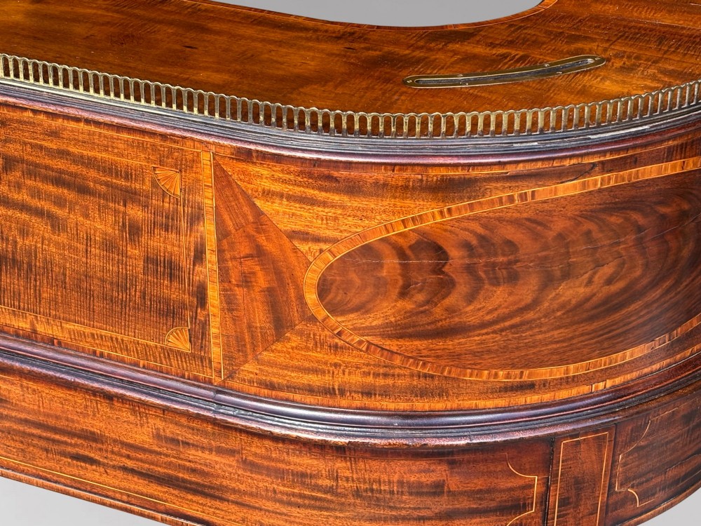 An 18th-century George III mahogany Carlton House desk with inlaid marquetry, a leather writing surface, small upper drawers, and tapered legs on brass castors. View XI