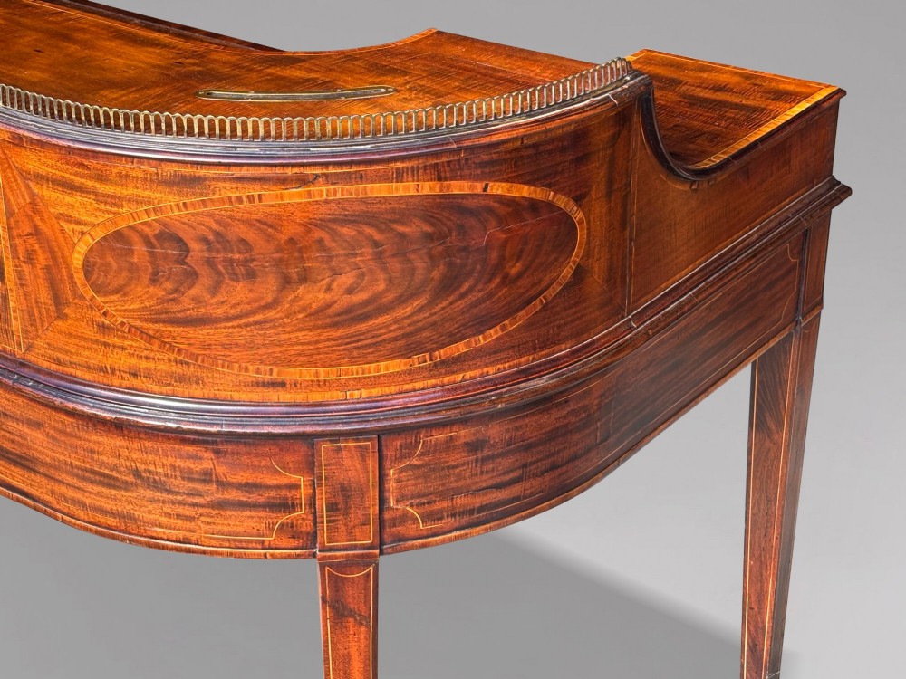 An 18th-century George III mahogany Carlton House desk with inlaid marquetry, a leather writing surface, small upper drawers, and tapered legs on brass castors. View XIII