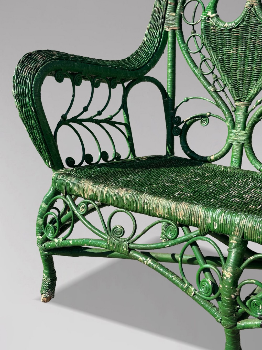 A French green painted wicker bench featuring two heart-shaped openwork back panels and curved armrests. View IV