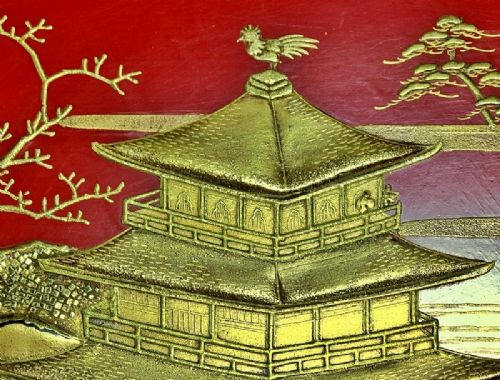 A large red lacquer Japanese sake cup decorated with gold maki-e motifs resting atop a dark brown wooden lacquer stand with a circular cutout. View XII