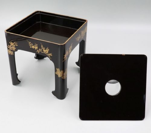 A square black lacquer miniature stand decorated with gold floral maki-e motifs, featuring a small matching black lacquer cup resting on top. View V