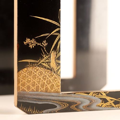 A Japanese black and gold lacquerware sake table featuring a raised stand, removable matching tray, and three red lacquer sakazuki cups adorned with painted gold motifs. View IX