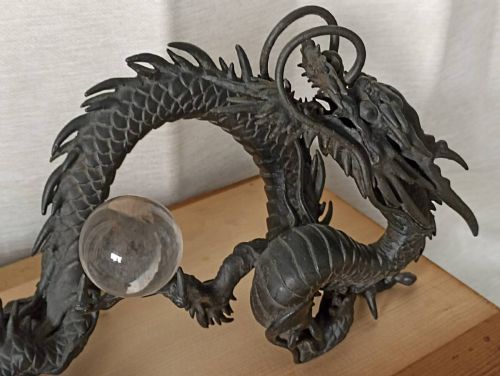 fig 1. A late 19th-century Japanese dark bronze dragon sculpture holding a clear glass sphere along its serpentine body.