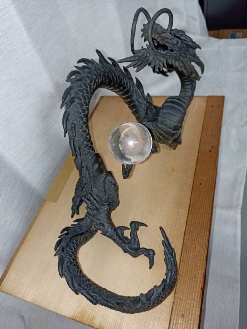 A late 19th-century Japanese dark bronze dragon sculpture holding a clear glass sphere along its serpentine body. View III