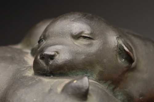fig 1. A dark patinated bronze sculpture depicting three sleeping puppies curled closely together.
