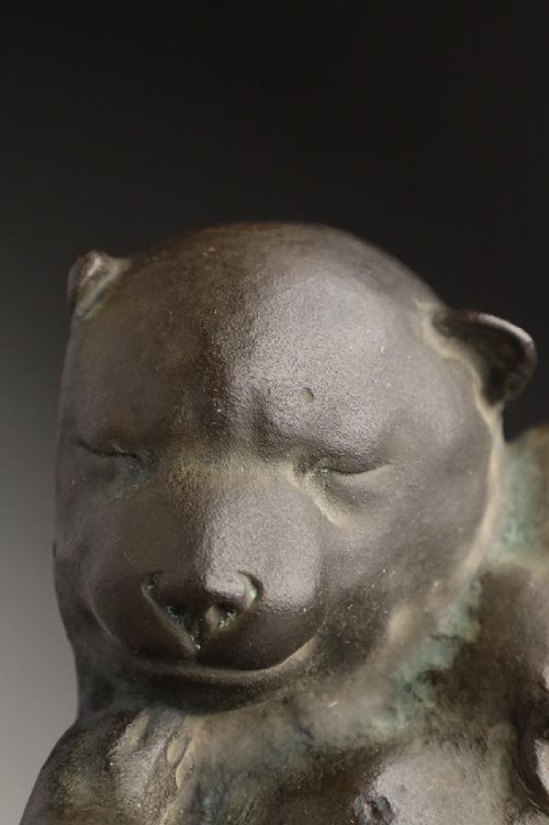 A dark patinated bronze sculpture depicting three sleeping puppies curled closely together. View V