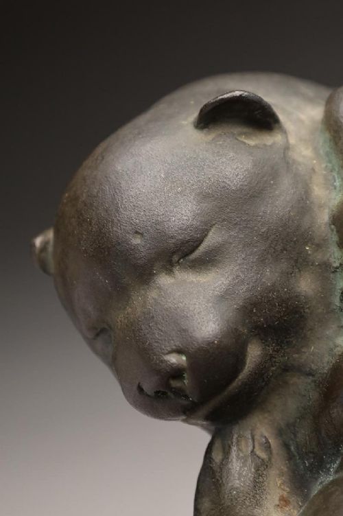 A dark patinated bronze sculpture depicting three sleeping puppies curled closely together. View VII