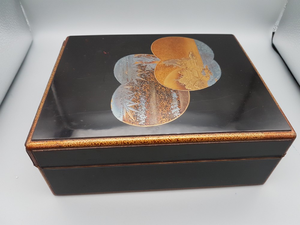 A rectangular black lacquer box featuring intricate gold and silver pictorial inlay depicting traditional Japanese landscapes within circular cartouches. View VII