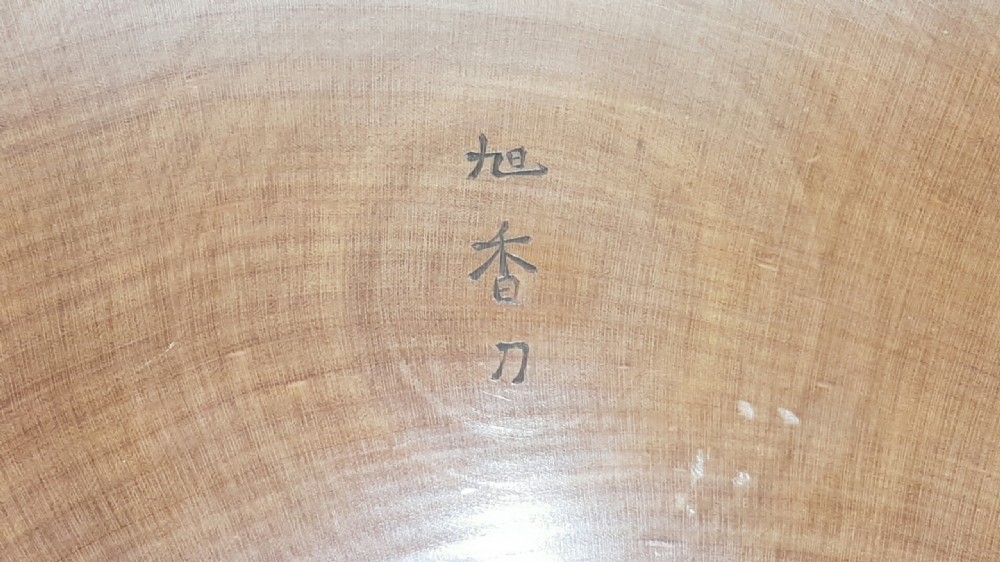 A stacked set of five shallow circular warm brown wood trays featuring low-relief carvings of traditional Japanese landscapes. View XIII