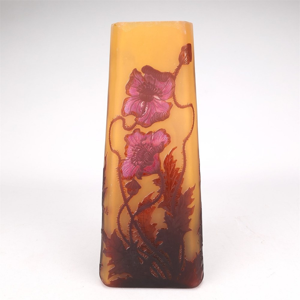 A tall tapered triangular cameo glass vase decorated with acid-etched red poppy blossoms and foliage on a frosted amber yellow background.