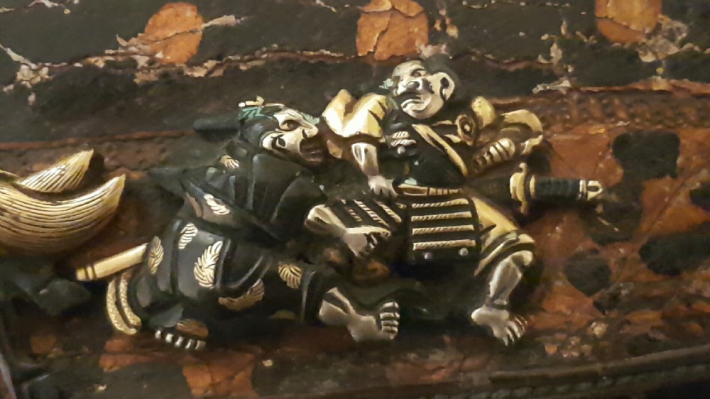 A rectangular dark brown tooled leather pouch featuring a metallic clasp decorated with embossed samurai figures on horseback in gold and silver. View XIII