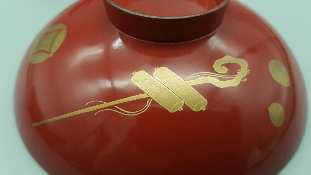 A set of four graduated Japanese red lacquer sake cups decorated with intricate gold maki-e illustrations including cranes, bamboo, and a rooster. View VIII