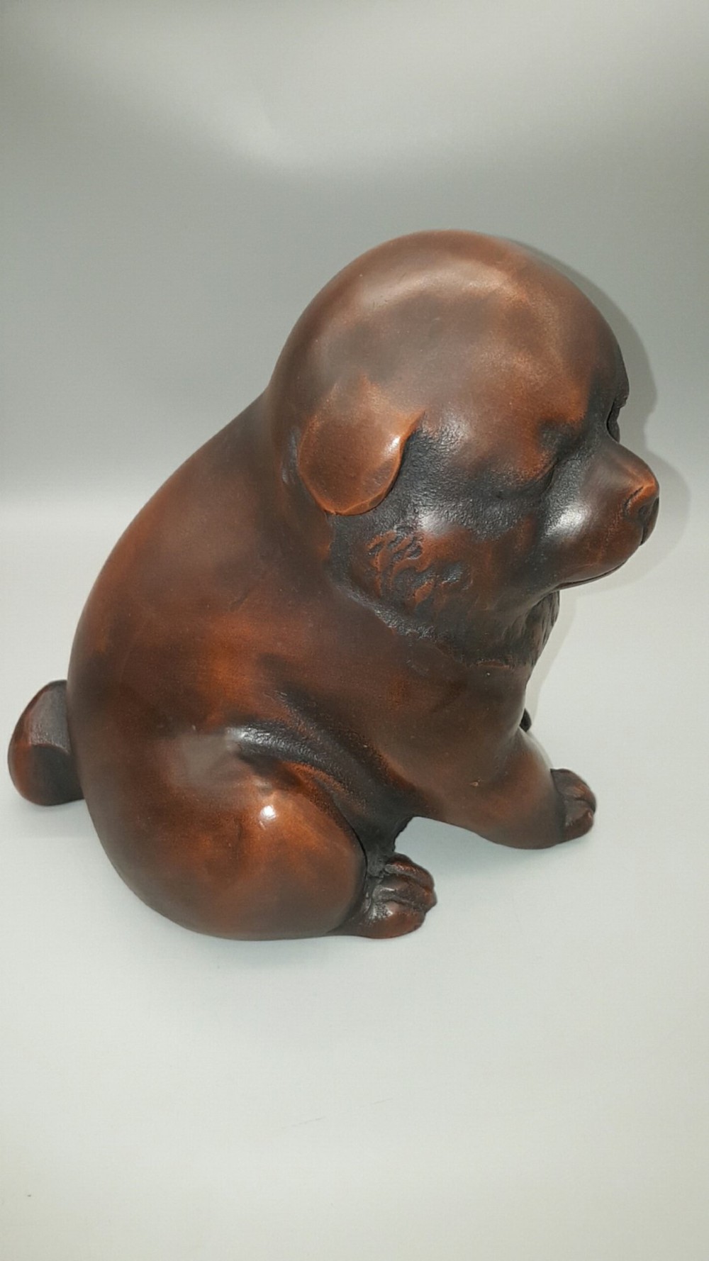 A cast bronze sculpture depicting a seated puppy with a warm brown patina and dark accents around its face. View II