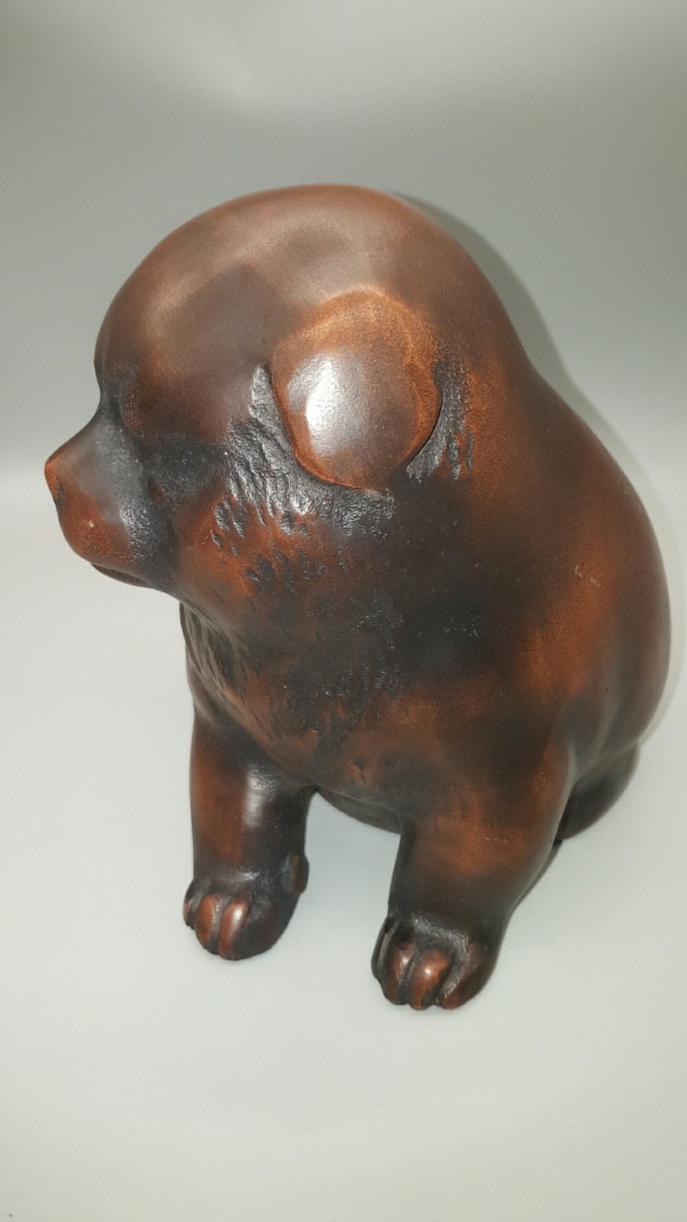 A cast bronze sculpture depicting a seated puppy with a warm brown patina and dark accents around its face. View III