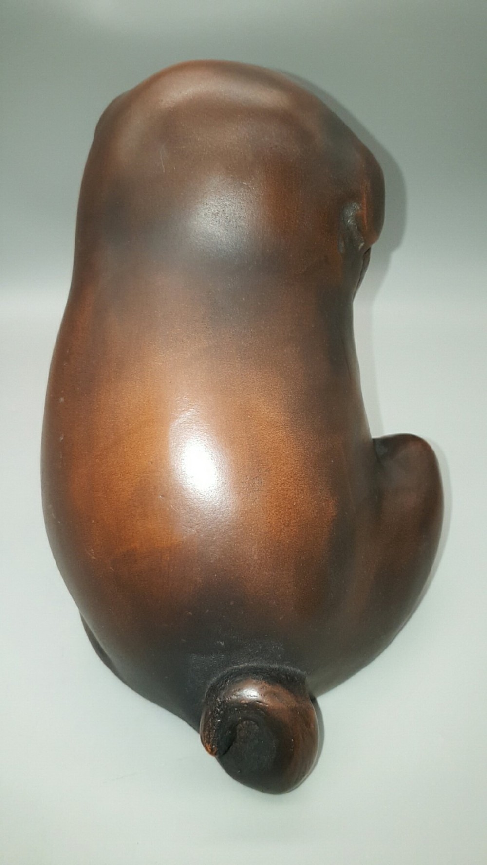 A cast bronze sculpture depicting a seated puppy with a warm brown patina and dark accents around its face. View V