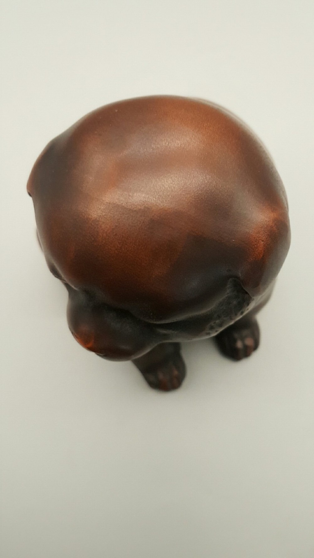 A cast bronze sculpture depicting a seated puppy with a warm brown patina and dark accents around its face. View VI