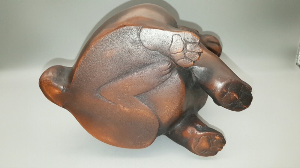 A cast bronze sculpture depicting a seated puppy with a warm brown patina and dark accents around its face. View VII
