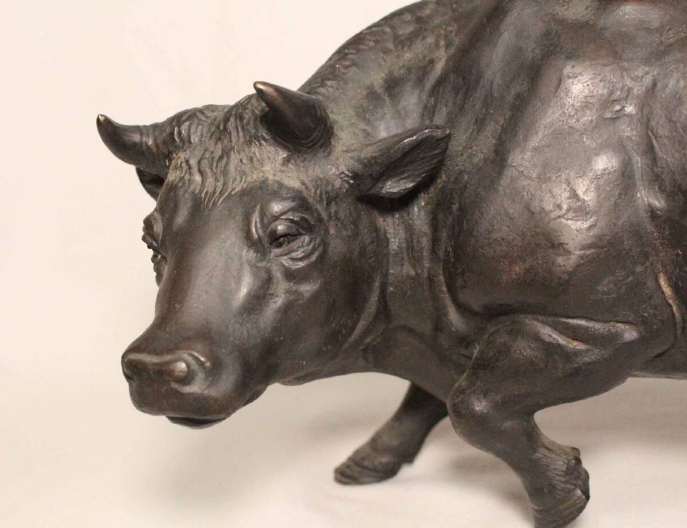 A late nineteenth-century Japanese cast bronze sculpture depicting a young boy seated atop a walking ox with a dark brown patina. View VI