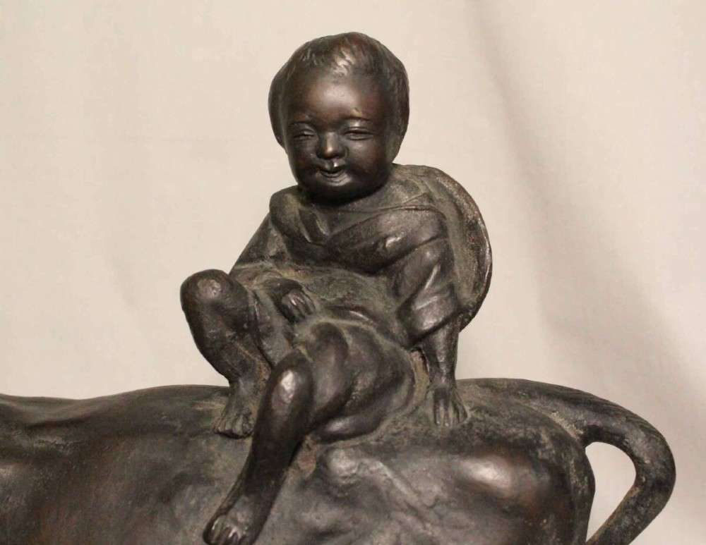 A late nineteenth-century Japanese cast bronze sculpture depicting a young boy seated atop a walking ox with a dark brown patina. View VII