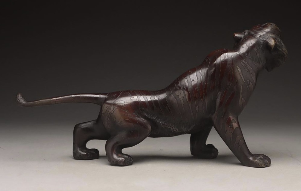 A dark patinated bronze sculpture depicting a snarling tiger in a low prowling stance with inset yellow crystal eyes. View II