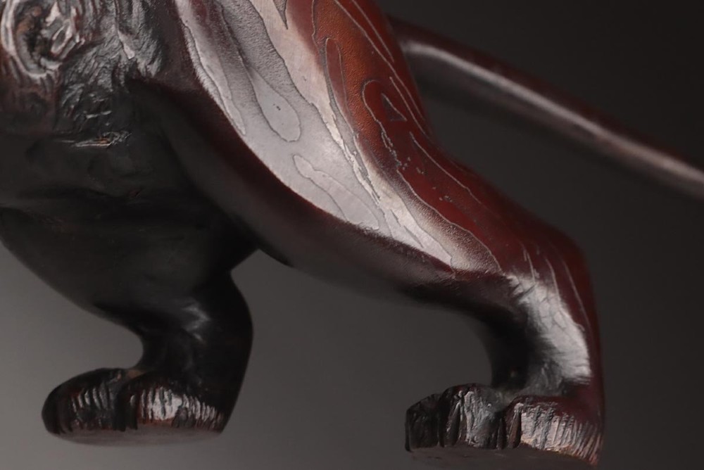 A dark patinated bronze sculpture depicting a snarling tiger in a low prowling stance with inset yellow crystal eyes. View IX