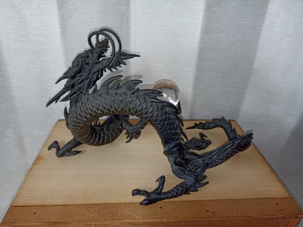 A late 19th-century Japanese dark bronze dragon sculpture holding a clear glass sphere along its serpentine body. View IV