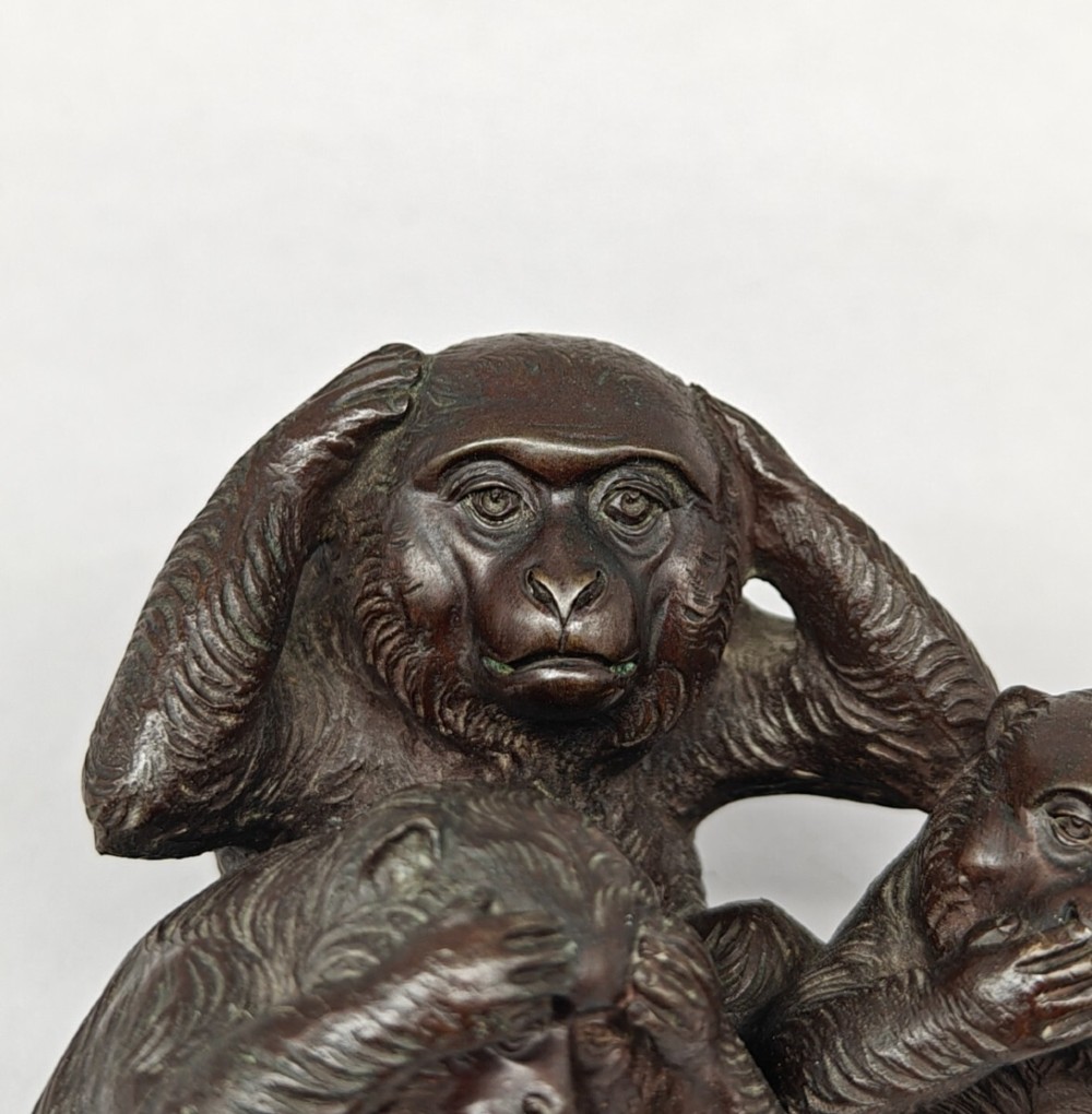 A patinated dark bronze sculpture depicting three monkeys seated together representing the motif of see no evil, hear no evil, and speak no evil. View II