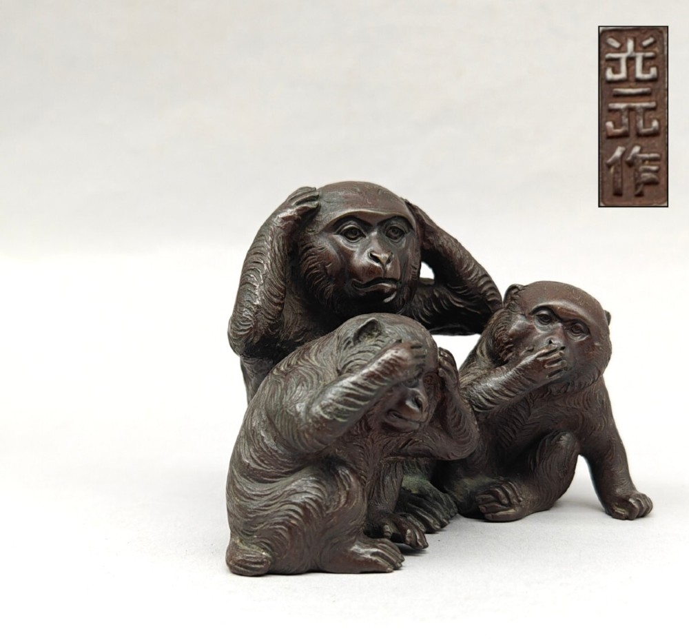 A patinated dark bronze sculpture depicting three monkeys seated together representing the motif of see no evil, hear no evil, and speak no evil. View V