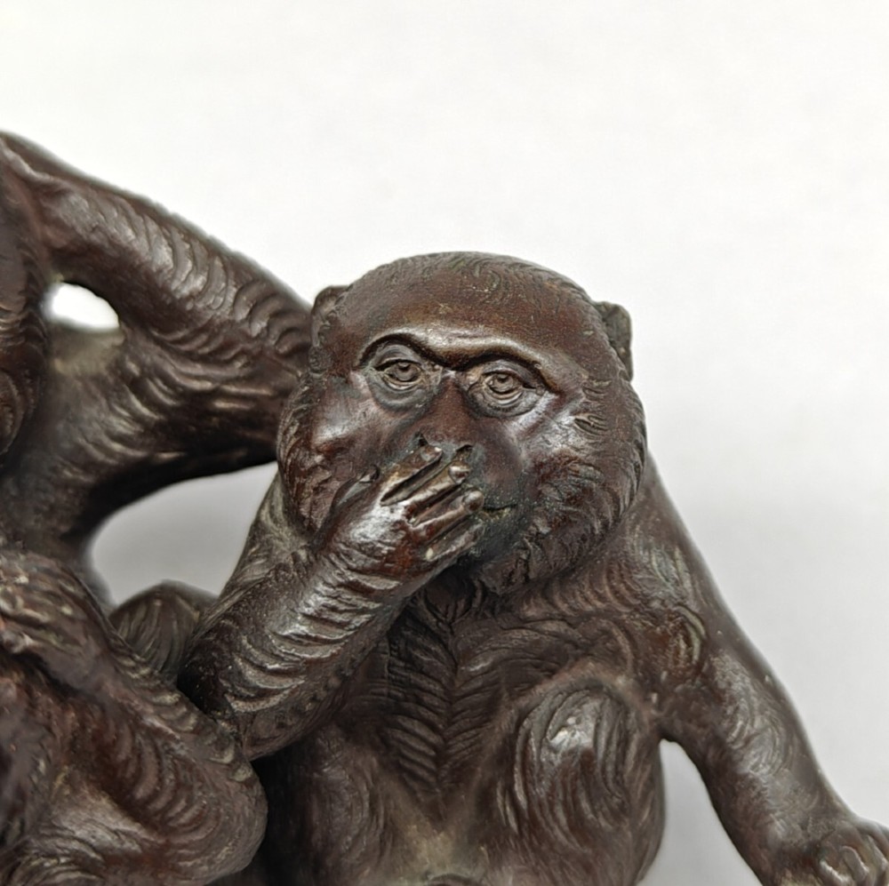 A patinated dark bronze sculpture depicting three monkeys seated together representing the motif of see no evil, hear no evil, and speak no evil. View VII