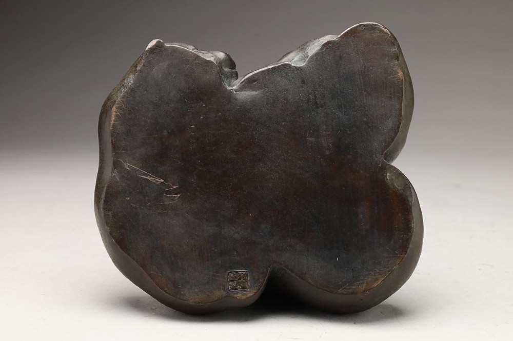 A dark patinated bronze sculpture depicting three sleeping puppies curled closely together. View IX