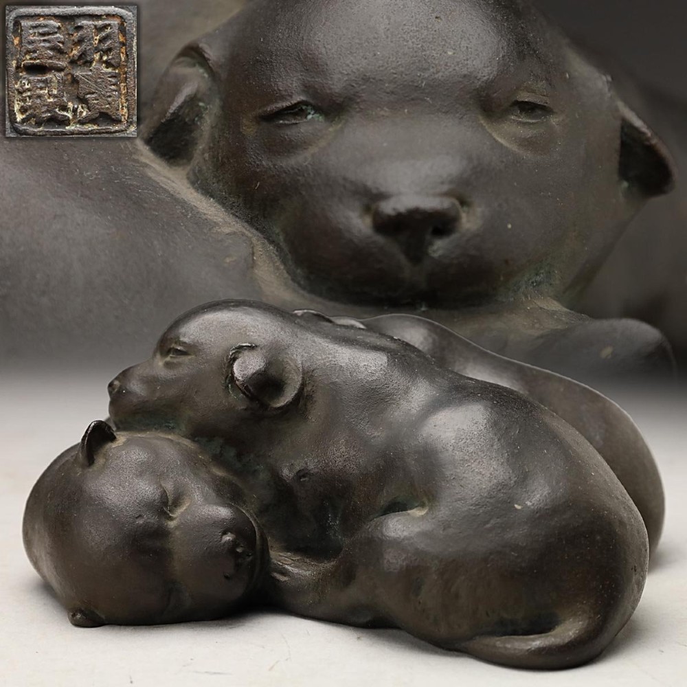 A dark patinated bronze sculpture depicting three sleeping puppies curled closely together. View XI