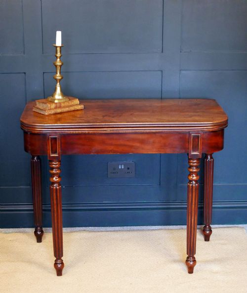 fig 1. A nineteenth-century William IV mahogany fold-over tea table featuring reeded turned legs and a polished timber surface.