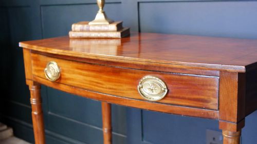 fig 2. A Regency mahogany demi-lune side table featuring a single drawer with oval brass handles and four slender turned legs.