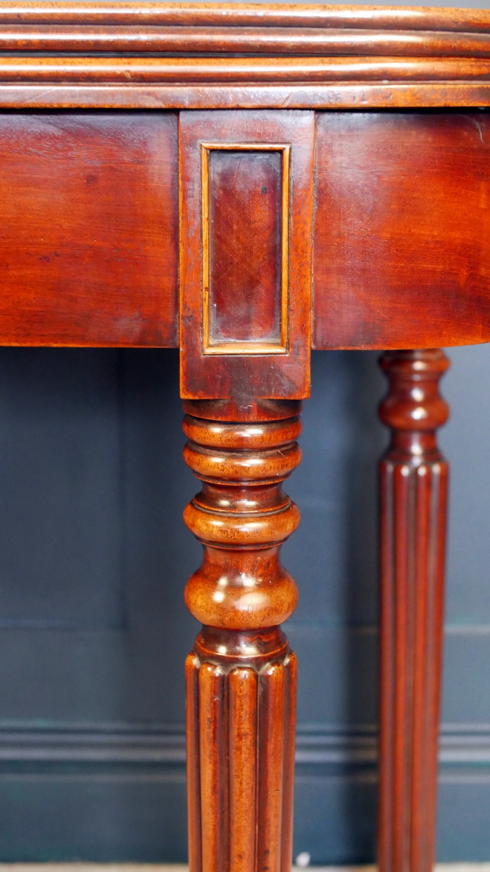 A nineteenth-century William IV mahogany fold-over tea table featuring reeded turned legs and a polished timber surface. View IV
