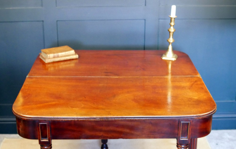 A nineteenth-century William IV mahogany fold-over tea table featuring reeded turned legs and a polished timber surface. View X