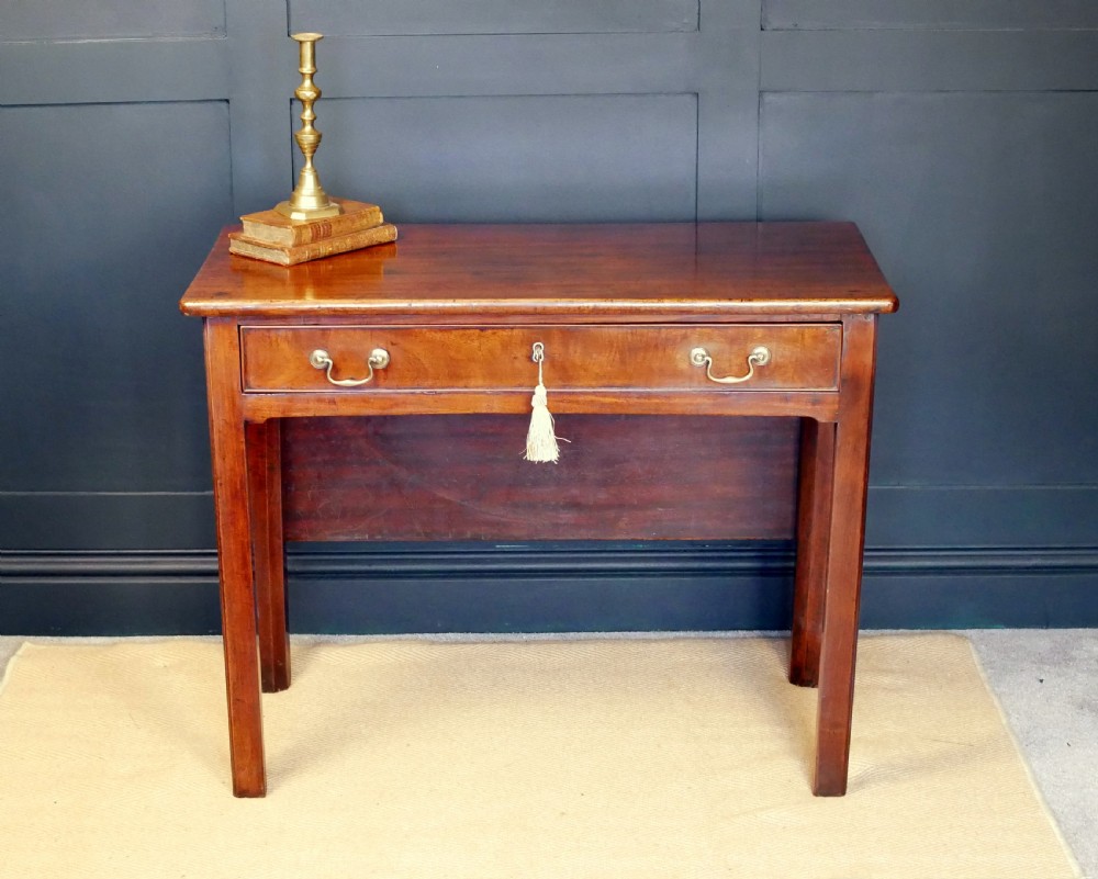 A George IV mahogany console table with a single frieze drawer, brass swan-neck handles, key tassel, and straight square legs.