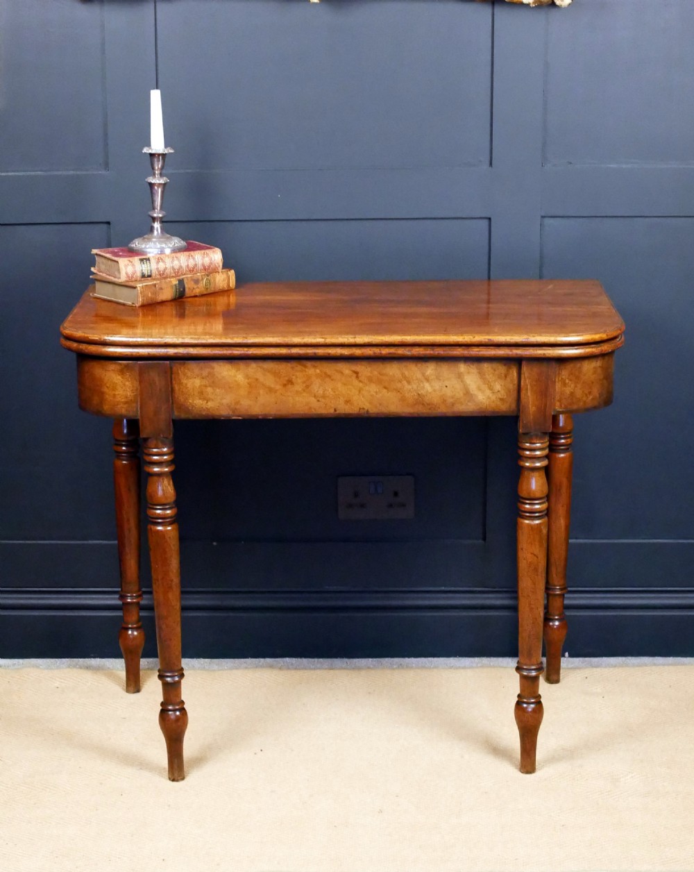 A Regency mahogany fold-over tea table featuring a rectangular hinged top with rounded corners, a deep frieze, and turned tapered legs.