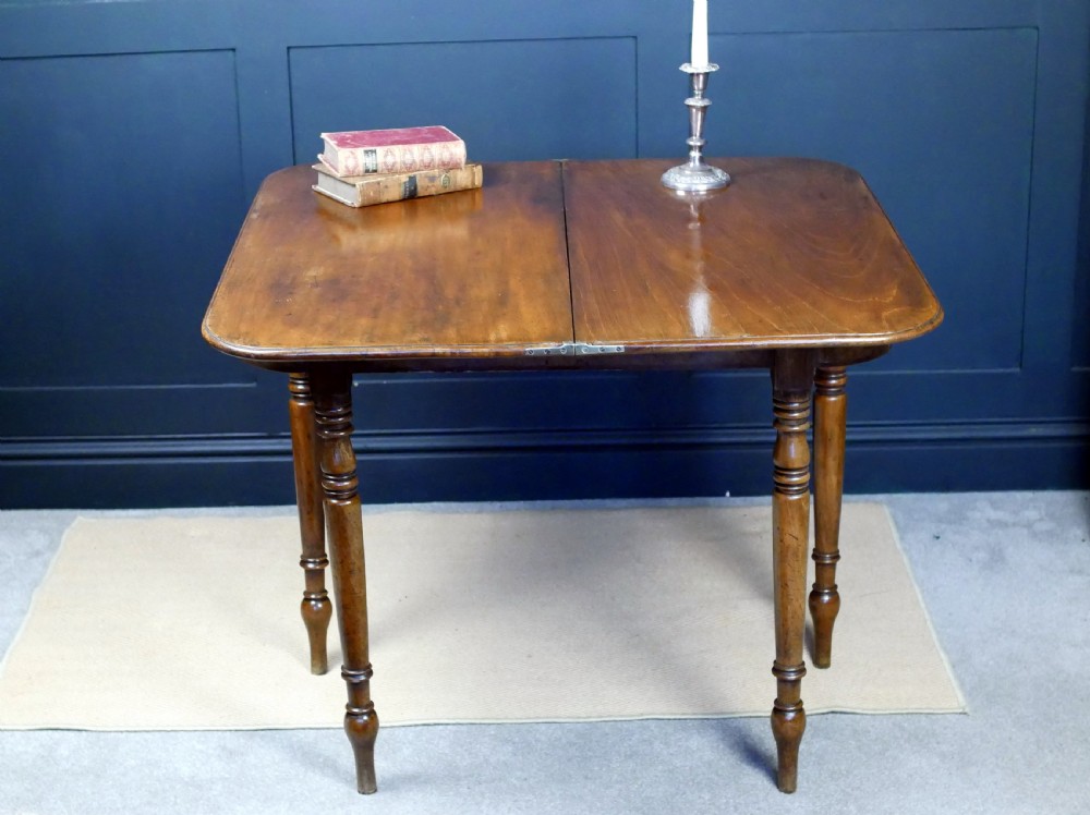 A Regency mahogany fold-over tea table featuring a rectangular hinged top with rounded corners, a deep frieze, and turned tapered legs. View X
