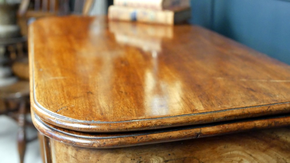 A Regency mahogany fold-over tea table featuring a rectangular hinged top with rounded corners, a deep frieze, and turned tapered legs. View XV