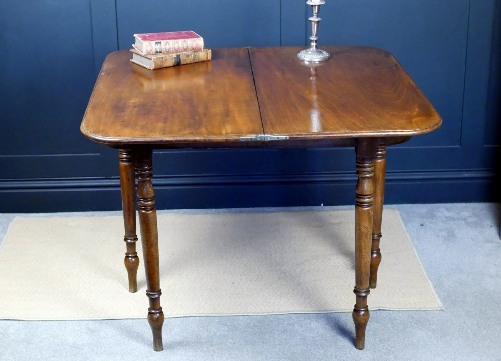 A Regency mahogany fold-over tea table featuring a rectangular hinged top with rounded corners, a deep frieze, and turned tapered legs. View XVI