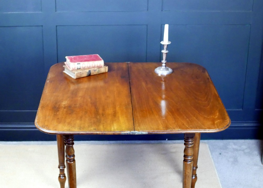A Regency mahogany fold-over tea table featuring a rectangular hinged top with rounded corners, a deep frieze, and turned tapered legs. View XVII