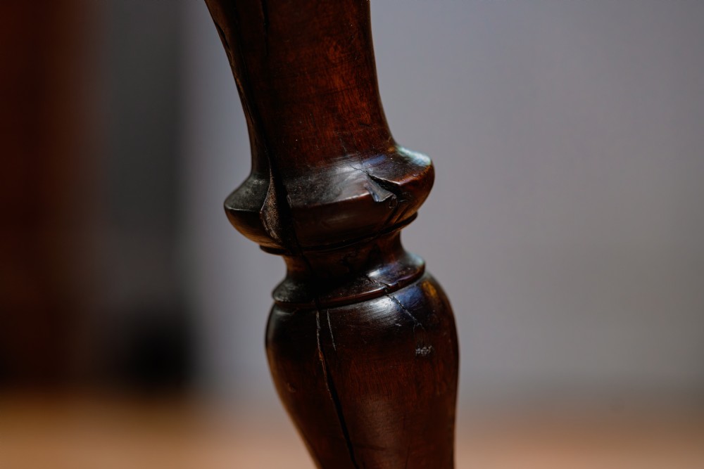 A dark brown wooden captains chair featuring a curved crest rail, turned spindles, a contoured saddle seat, and turned legs joined by stretchers. View X