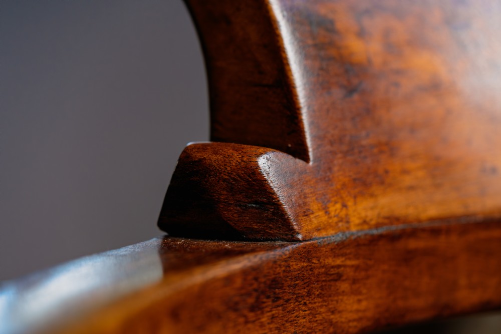 A dark brown wooden captains chair featuring a curved crest rail, turned spindles, a contoured saddle seat, and turned legs joined by stretchers. View XIV