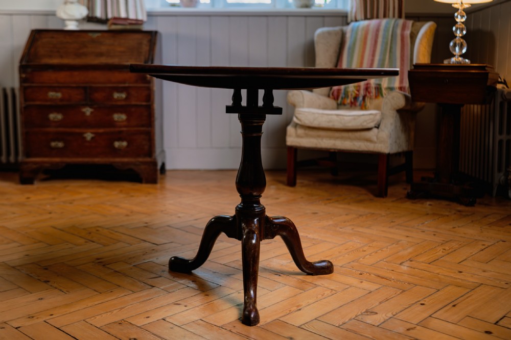 A Georgian mahogany tripod wine table featuring a circular top, turned column stem, and three cabriole legs.