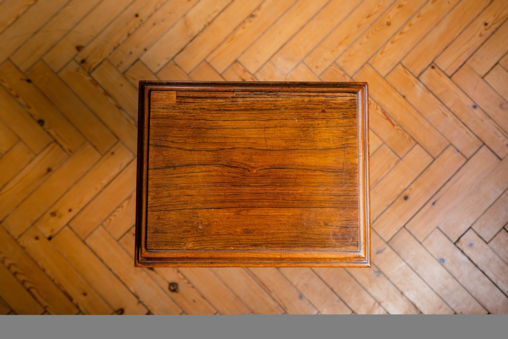 A Victorian rosewood teapoy featuring a rectangular hinged box top with a keyhole, supported by a tapered pedestal column on a four-pointed plinth base with scroll feet. View IX