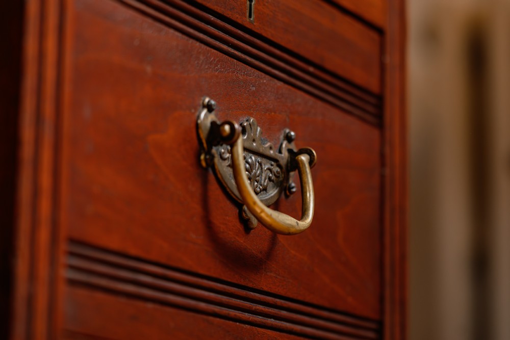 An antique warm brown walnut pedestal desk featuring nine drawers with brass handles and reeded moulding around a central kneehole. View VII