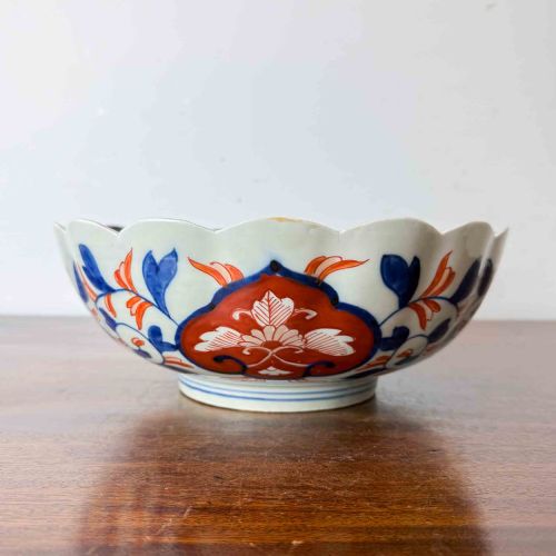 fig 1. A shallow Japanese Imari porcelain bowl featuring a scalloped rim, hand-painted floral panels in cobalt blue, iron-red enamel, and green accents on a white porcelain ground.