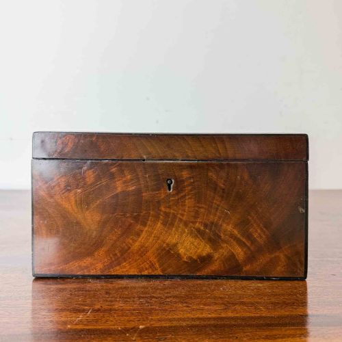 fig 1. A rectangular early Victorian tea caddy crafted from flame mahogany veneer with crossbanded inlaid borders and a central metal keyhole escutcheon.