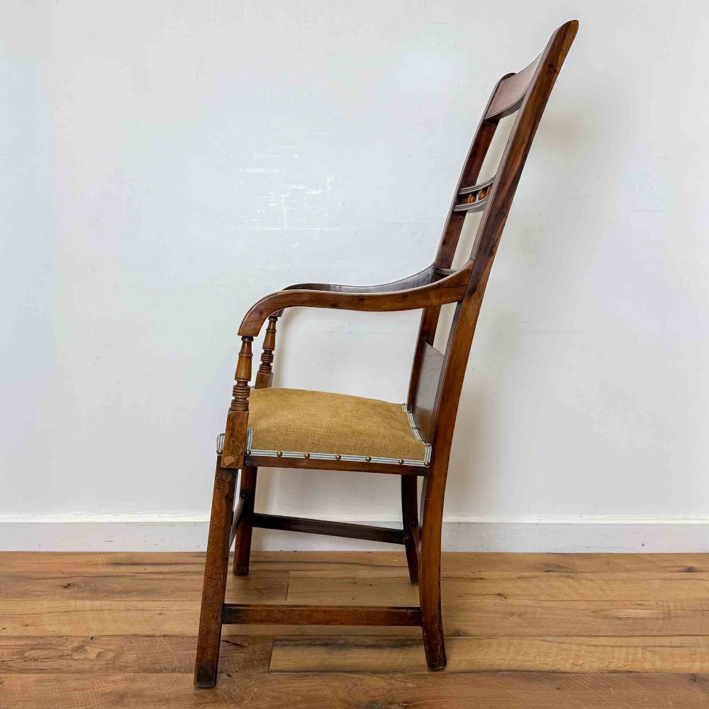 A Regency period high back open armchair crafted from fruitwood and elm with turned arm supports and a textured ochre upholstered seat. View II