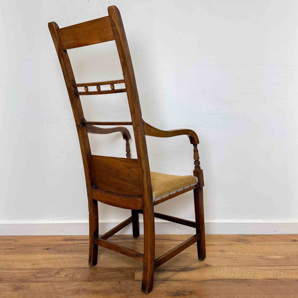 A Regency period high back open armchair crafted from fruitwood and elm with turned arm supports and a textured ochre upholstered seat. View V